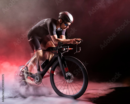 Sportsman sitting on turbo trainer against black background