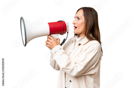 Middle-aged caucasian woman over isolated background shouting through a megaphone to announce something in lateral position