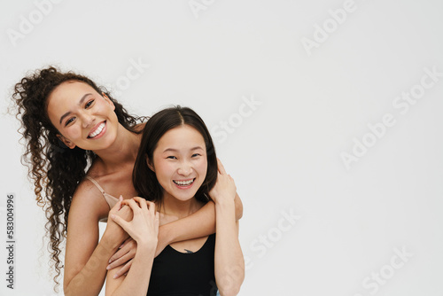 Two cheerful women posing isolated over white wall