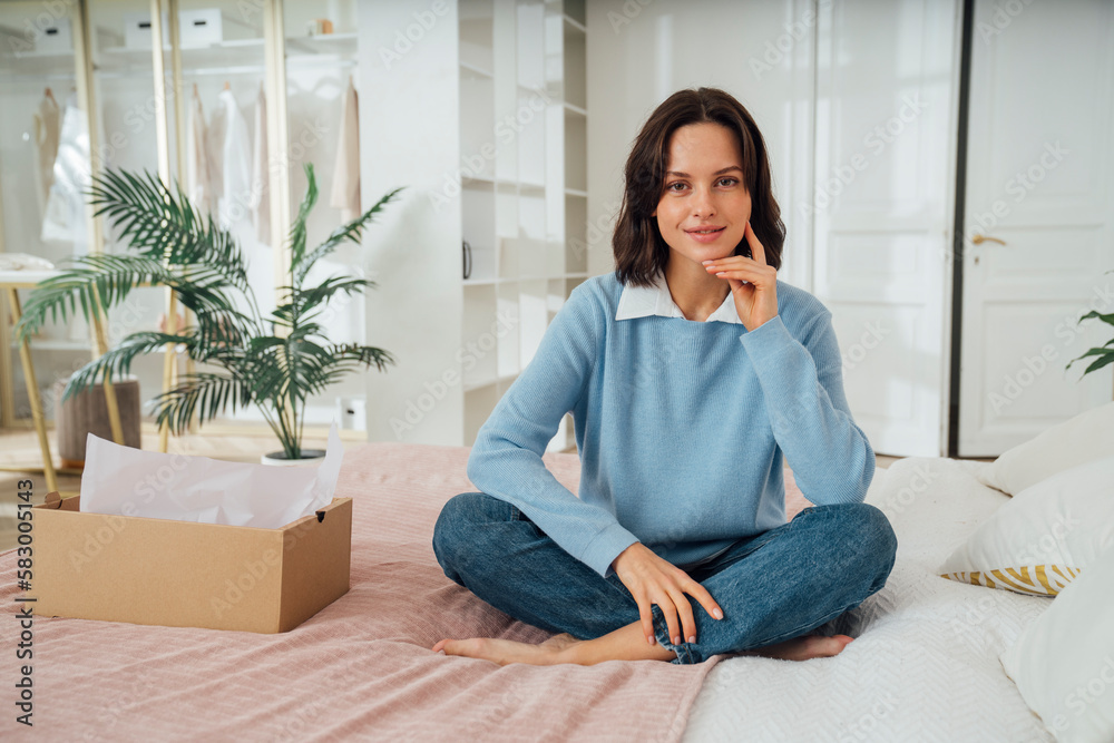 Smiling woman sitting on bed at home Smiling woman sitting on bed at home
