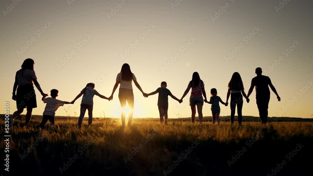 Big happy family. Group of people have fun walking in the park on green grass. Parents and children walk together holding hands at sunset. Family love and support. Family teamwork in park on vacation
