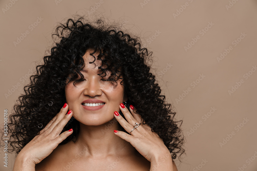 Beautiful asian woman smiling and touching her face while standing isolated Beautiful asian woman smiling and touching her face while standing isolated