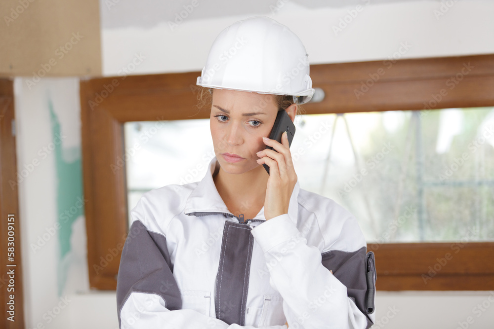 young woman builder with serious expression on the phone young woman builder with serious expression on the phone
