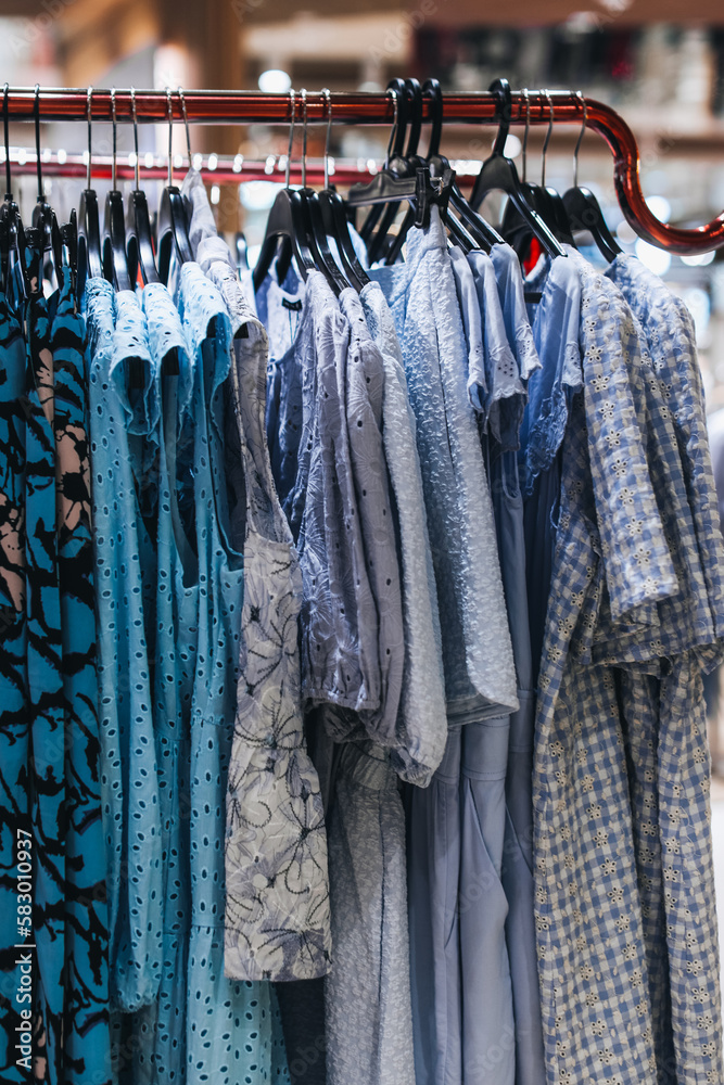 Blue women's clothes dresses hanging on a hanger in a row. Fashion collection Blue women's clothes dresses hanging on a hanger in a row. Fashion collection