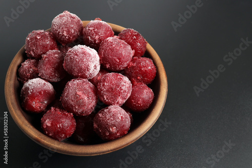 Frozen cherries in a bowl on a dark background