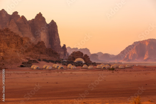 Camp site tents at Wadi Rum Desert, Jordan and red rocks sunset landscape