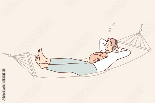 Guy lying with cat in hammock listen to music 