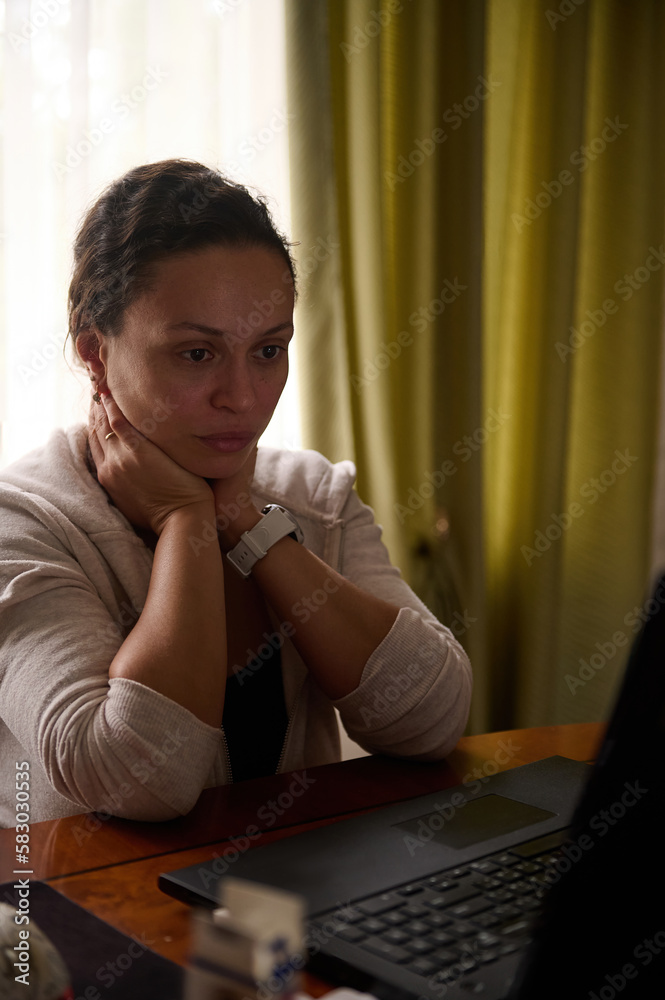 Freelancer woman sitting at laptop, feeling stressed out and dizzy from her job, telecommuting from home office. Tired and worn out from online work young woman sitting in front laptop, holding head Freelancer woman sitting at laptop, feeling stressed out and dizzy from her job, telecommuting from home office. Tired and worn out from online work young woman sitting in front laptop, holding head