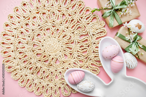 Photography plate rabbit, easter eggs, gifts with green ribbon, spring sakura flowers on a pastel pink background