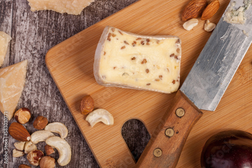 Different type of cheese and nuts on vintage wooden background in studio photo