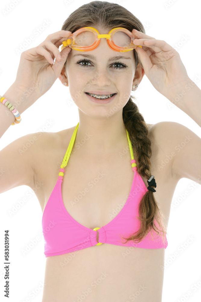 Teenage girl in pink bikini is wearing swimming goggles in studio isolated on white