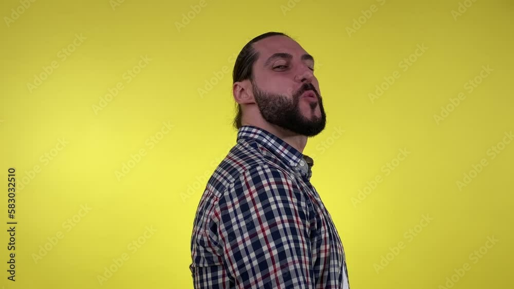 Playful male person wearing casual cloth flirting, showing finger pistols at camera indoors. Portrait bearded man pointing fingers at camera, winking, looking at camera isolated on yellow background. Playful male person wearing casual cloth flirting, showing finger pistols at camera indoors. Portrait bearded man pointing fingers at camera, winking, looking at camera isolated on yellow background.