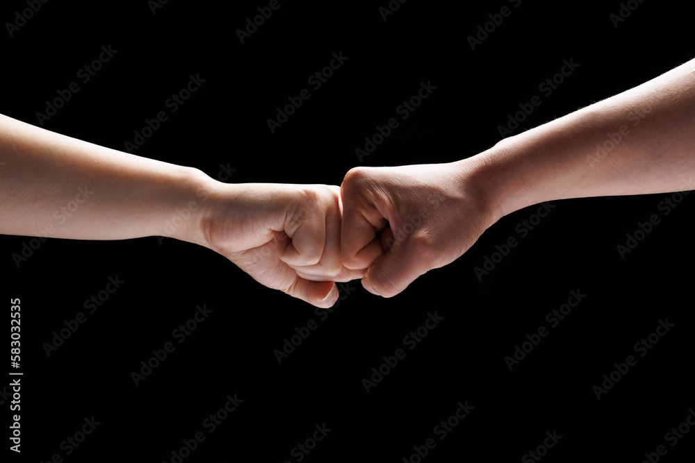 Two people are greeting each other with their fists as a COVID-19 greeting