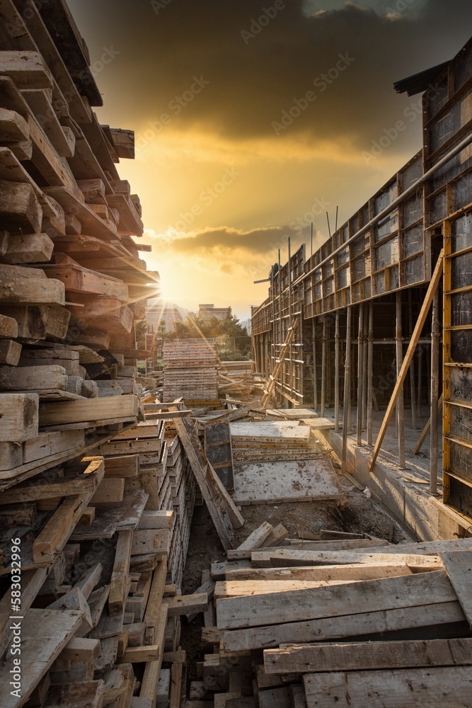 The construction site is full of old pieces of wood and dirt, sunset light.