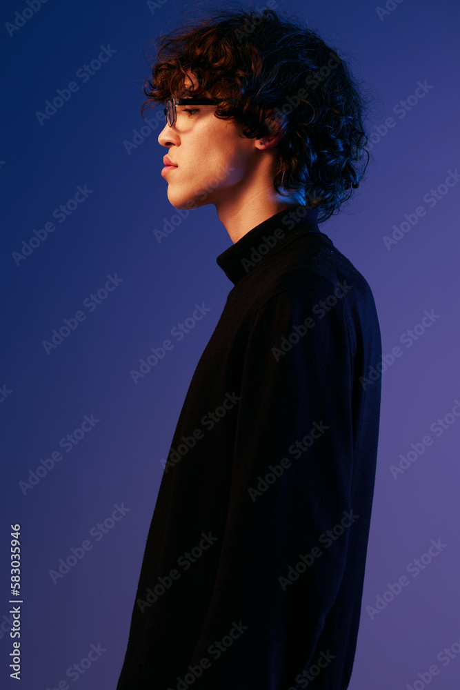 Male fashion in black model poses in glasses, hipster lifestyle, portrait blue background, mixed neon light, fashion style and trends boys teenager, copy space