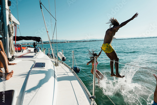 Happy friends diving from sailing boat into the sea - Focus on girl face - Travel and summer concept © DisobeyArt