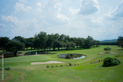Wide shot of a golf course with a sand trap and water hazard.