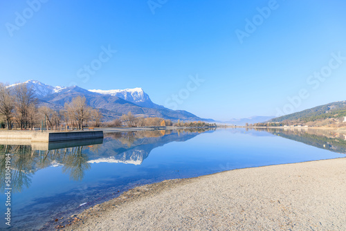 Fototapeta Naklejka Na Ścianę i Meble -  A scenics view of the Embrun, France lake with snowy mountains range in the background under a majestic blue sky