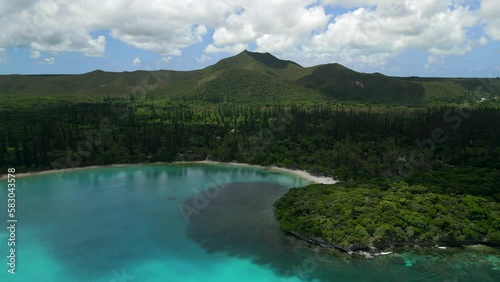 The lagoon in the crystal clear water of Kanumera Bay on the Isle of Pines - pull back aerial flyover photo