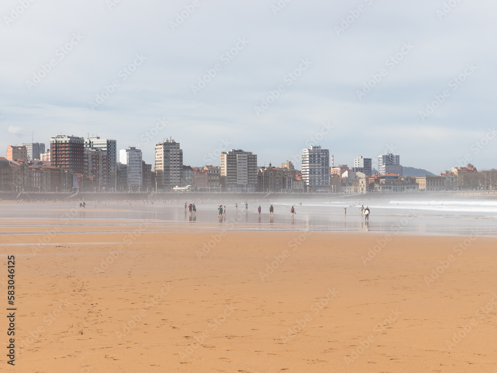 Beautiful landscape of San Lorenzo Beach in Gijón, Asturias, Spain. People walking on the beach at the weekend.