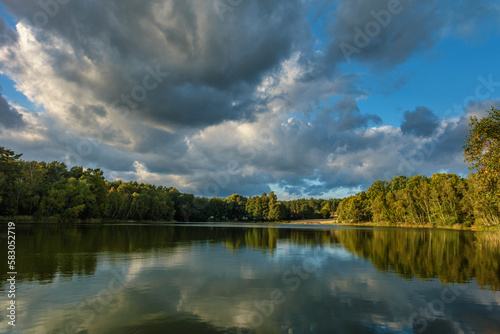 Fototapeta Naklejka Na Ścianę i Meble -  Natural landscape of the lake, high definition, the movement of waves against the background of the autumn forest. The reflection of clouds on the ripples of water. Germany.