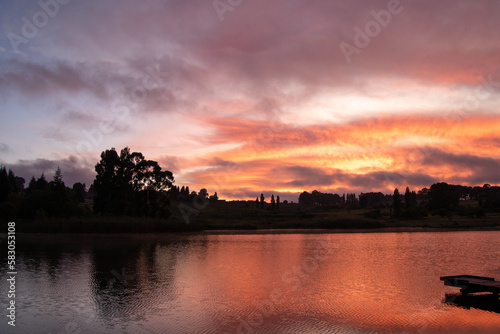 Fiery orange sunrise over a dam photo