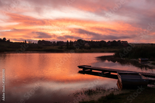 Fiery orange sunrise over a dam photo