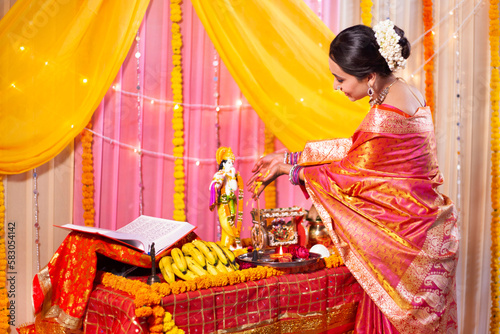 Indian ethnic woman offering flowers to Lord Krishna during festivities . Indian woman in traditional wear worshiping Lord Krishna with flowers 