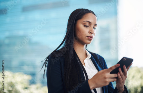 Mobile tech helps get more done on the move. a young businesswoman using a smartphone against a city background.