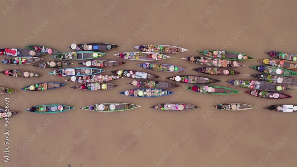 Colorful boats on brown river getting pulled by motorboat, floating market, top down Colorful boats on brown river getting pulled by motorboat, floating market, top down