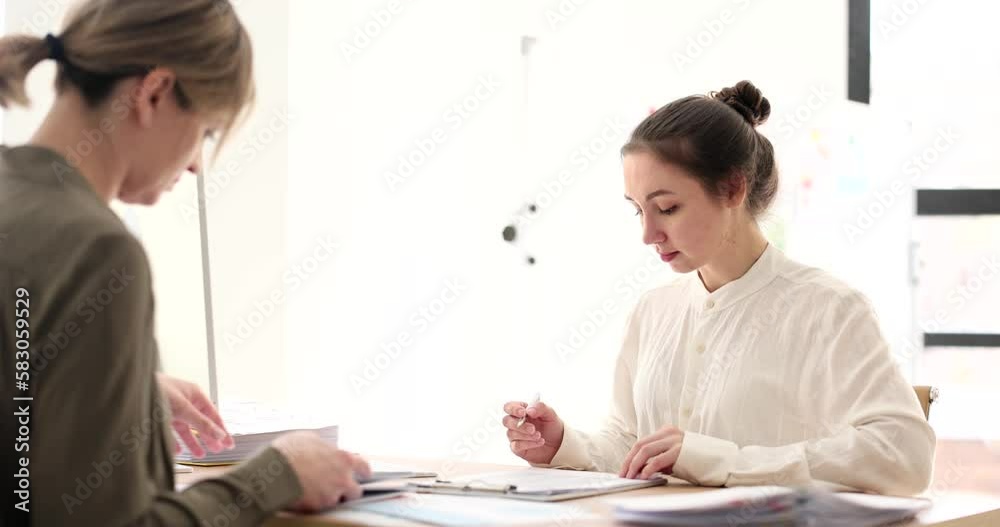 Two women at the table work together with documents Two women at the table work together with documents