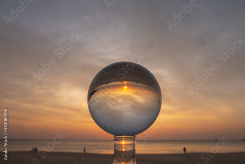 view of colorful nature at sunset inside crystal ball..beautiful sunset over sea in a crystal ball on the beach. .Nature High quality footage in nature and travel concept. © Narong Niemhom