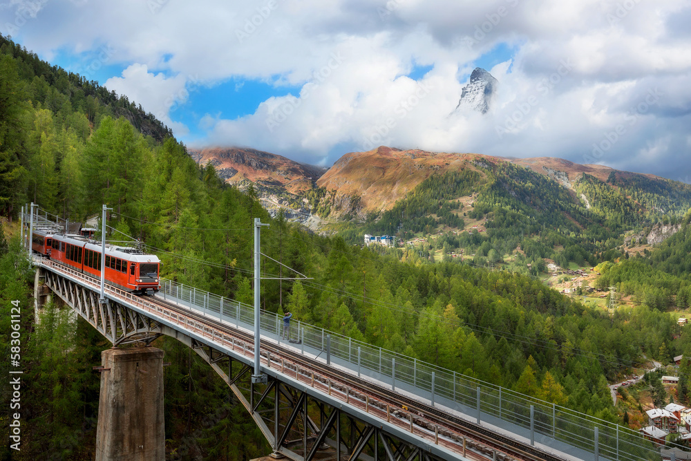 Zermatt, Switzerland. Gornergrat red tourist train on the bridge and Matterhorn peak panorama in Swiss Alps
