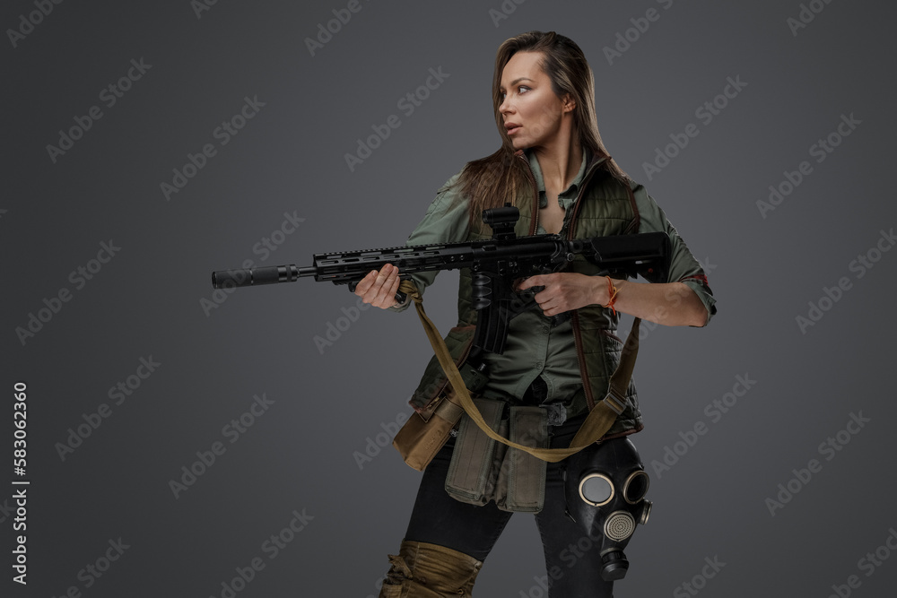 Portrait of military woman with rifle looking to side isolated on grey background.