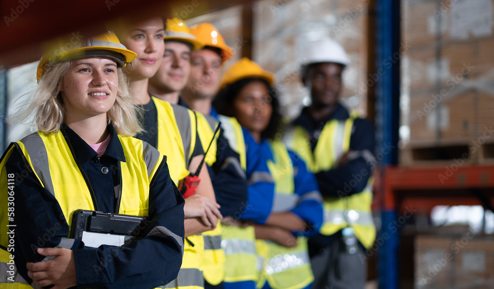 Multiracial group of men and women workers standing in merchandise storage warehouse in factory. Multiethnic people and colleagues working together, portrait. Diverse people teamwork. Selective focus Multiracial group of men and women workers standing in merchandise storage warehouse in factory. Multiethnic people and colleagues working together, portrait. Diverse people teamwork. Selective focus
