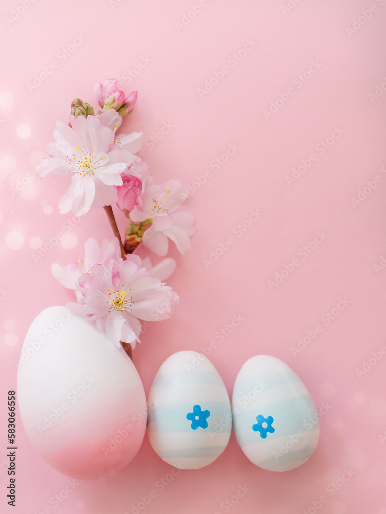 Easter eggs and cherry flowers on a pink background with bokeh and copy space. Vertical photo