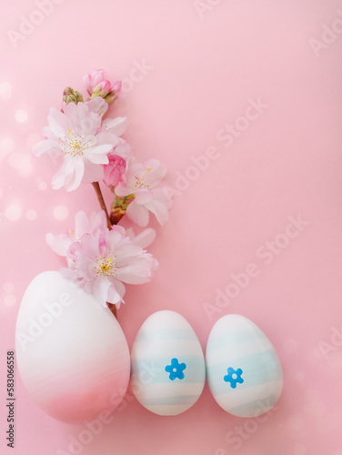 Easter eggs and cherry flowers on a pink background with bokeh and copy space. Vertical photo