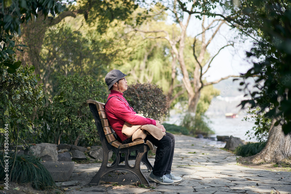 Senior Asian woman sitting in chair alone looking at lake Senior Asian woman sitting in chair alone looking at lake