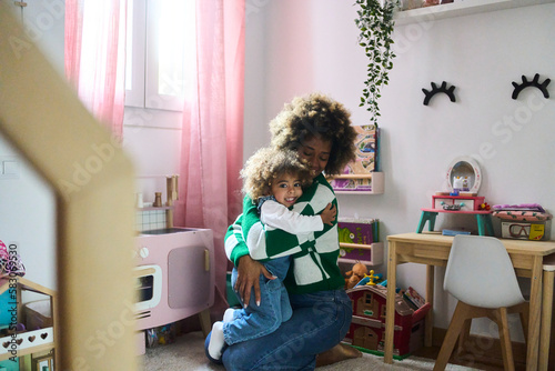 young black mother with fizzy hair and her little doughtier playing with educational toys in her room