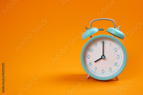 Retro green alarm clock on orange table background, vintage style