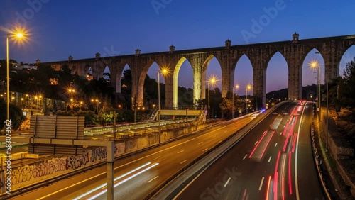 Time-lapse of highway traffic near Campolide station with Aguas Livres Aqueduct in background in the evening with car lights trails. Lisbon, Portugal photo