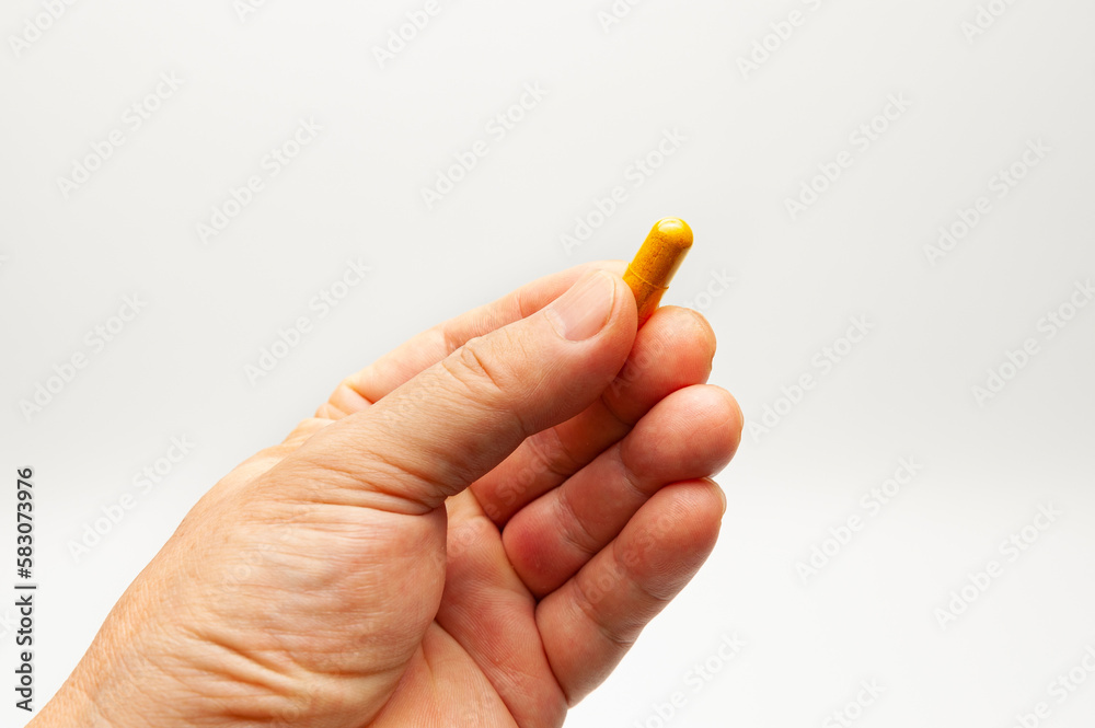 Man hand holding Turmeric supplement capsule isolated on white background with copy space Man hand holding Turmeric supplement capsule isolated on white background with copy space