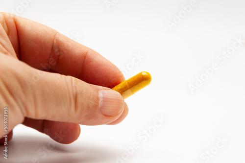Man hand holding Turmeric supplement capsule isolated on white background with copy space