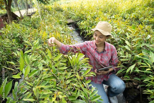 Φωτογραφία Female farmer using digital tablet while observing plant seeds in polybags in nu