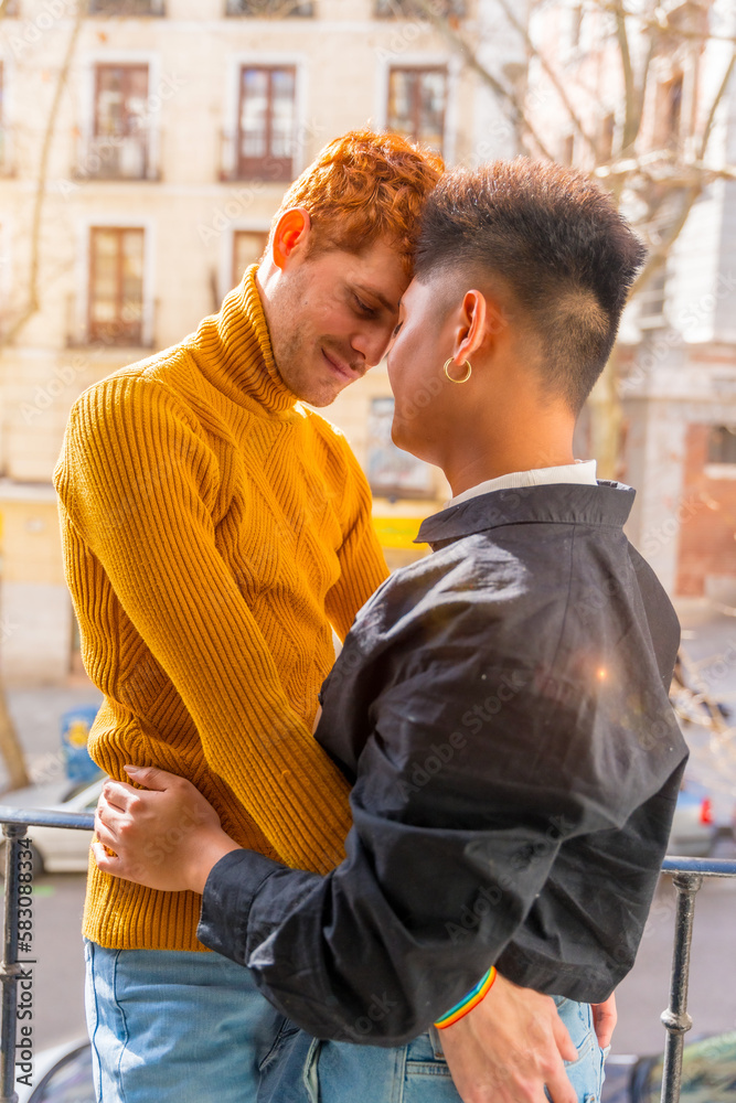 Fototapeta premium Beautiful gay couple being romantic at home on sofa, home balcony, lgbt concept