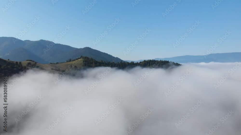 High above sea of clouds aerial view. European mountain valley forest and peaks reveal over misty morning clouds High above sea of clouds aerial view. European mountain valley forest and peaks reveal over misty morning clouds