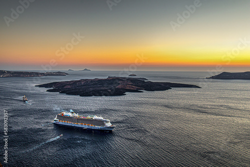 cruise boat at sunset over caldera volcano in santorini