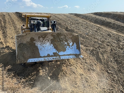 Bulldozers working at huge mining site, leveling the ground, pushing soil.