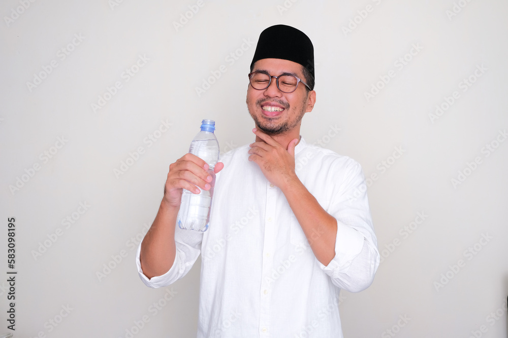 Moslem Asian man showing relieved expression after drink a water Moslem Asian man showing relieved expression after drink a water