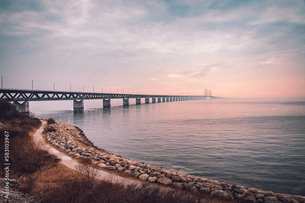 The Oresund Bridge is a combined motorway and railway bridge between Sweden and Denmark (Malmo and Copenhagen). Captured on a foggy spring day before sunset. - obrazy, fototapety, plakaty 
